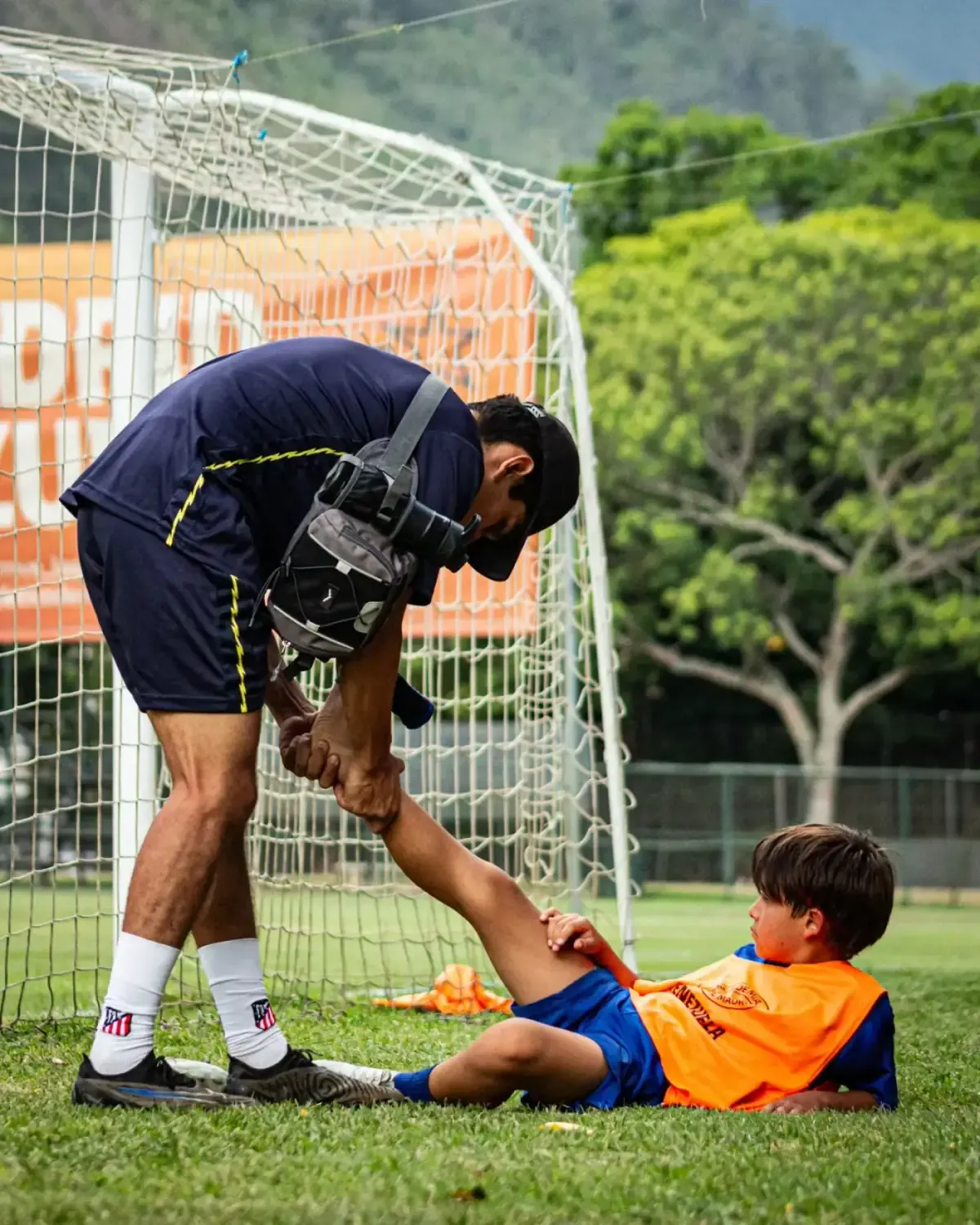 Andrés Correia atendiendo a un atleta en el suelo, junto a la portería, durante una sesión.